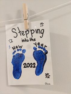 a sign hanging from a clothes line that says stepping into the new year with two footprints