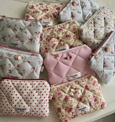 several small purses sitting on top of a table next to each other, all covered in pink and white flowers