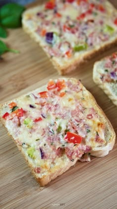 four slices of bread with different colored toppings on them sitting on a cutting board