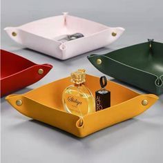 three different colored trays with perfume bottles in them