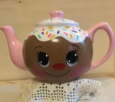 a tea pot with a face painted on it and sprinkles around the top