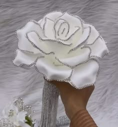 a hand holding a white rose with diamonds on it