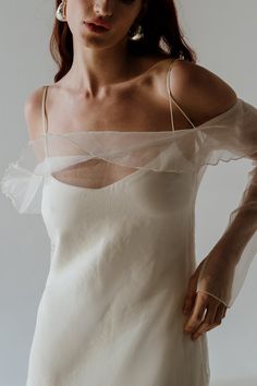 a woman wearing a white dress with sheer sleeves and pearls on her head is posing for the camera