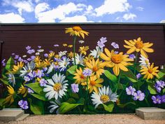 a mural painted on the side of a building with yellow and white flowers in it