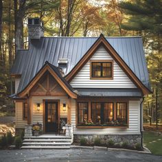 a white house with a metal roof in the woods