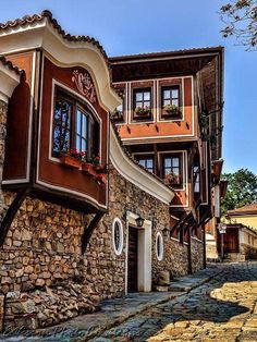 a cobblestone street lined with stone buildings and flowers on the windows above them