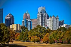 the city is full of tall buildings with trees in front of them and blue sky