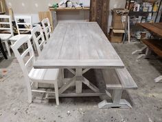 a wooden table with white chairs around it in a room filled with other furniture and tools