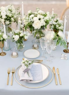 the table is set with white flowers and silverware for an elegant wedding reception in france