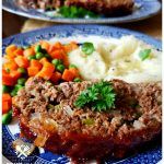 meatloaf with mashed potatoes, carrots and peas on a blue plate