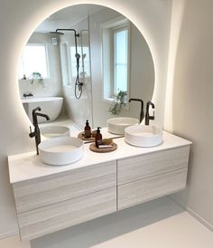 a bathroom with two sinks and a large round mirror