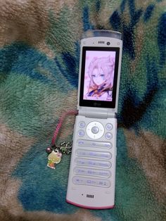 a cell phone with a keychain attached to it sitting on a floral blanket