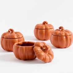 three small pumpkins are sitting next to each other on a white surface with the lid open