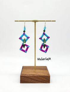 a pair of earrings is displayed on a wooden stand with the word valeriem written below it