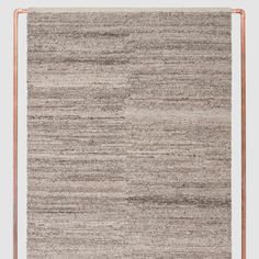 an area rug with brown and white stripes on the bottom, in front of a gray background