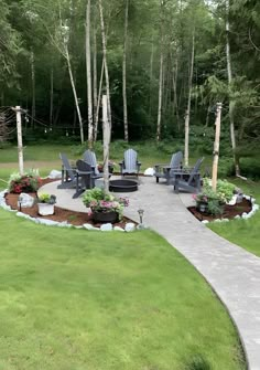 an outdoor patio with chairs and flowers in the center, surrounded by tall trees on either side