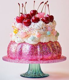 a cake with white frosting and cherries sitting on top of a pink plate