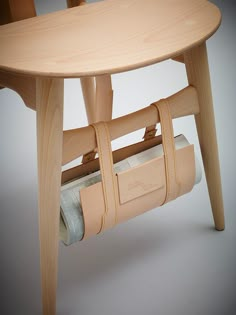 a wooden chair with a roll of toilet paper on it's back and strap around the seat