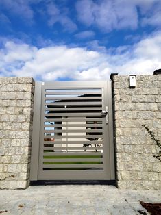 an open gate on the side of a stone wall with grass growing in front of it