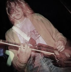 a man with long hair playing an electric guitar