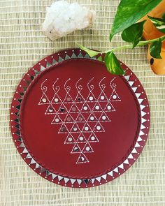 a red plate sitting on top of a table next to a plant