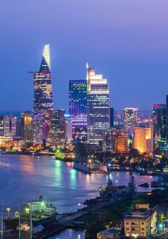 the city skyline is lit up at night with bright lights and skyscrapers in the background