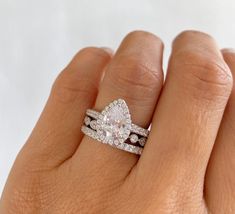 a woman's hand with two wedding rings on top of her finger and an engagement ring in the middle