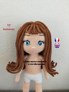 a crocheted doll with long hair and blue eyes