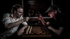 two men sitting at a table playing chess