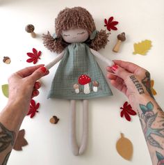 two hands are holding a doll made out of fabric