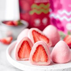 some strawberries are cut in half on a white plate and placed on a marble surface