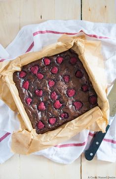 a chocolate cake with raspberries on top is sitting on a napkin next to a knife