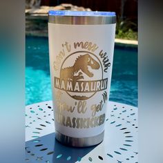 a stainless steel tumbler sitting on top of a table next to a swimming pool