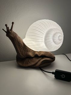 a snail lamp sitting on top of a table next to a charger and power cord