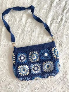 a blue crocheted purse sitting on top of a bed