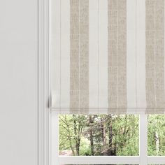 an open window with white and beige striped roman shades on the windowsill, in front of trees