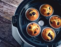 several muffins are sitting in the middle of an air fryer on a wooden table