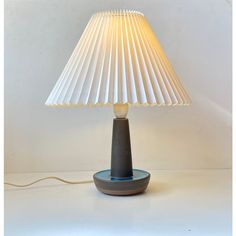 a lamp that is sitting on top of a table next to a white wall behind it