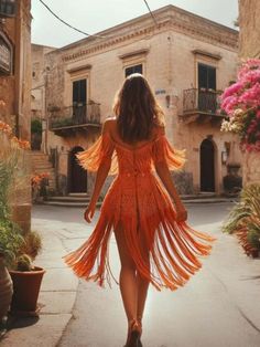 a woman in an orange dress is walking down the street with her back to the camera