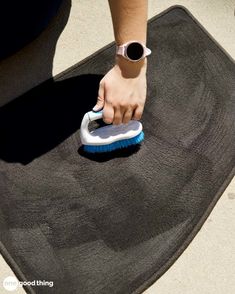 a person using a brush to clean a car mat on the floor with a sponge