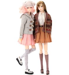 two dolls standing next to each other in front of a white background and one is wearing a skirt