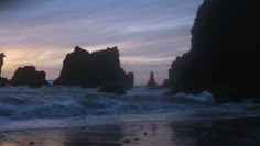 the sun is setting over some rocks in the ocean