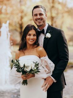 a bride and groom pose for a photo in front of a fountain at their wedding