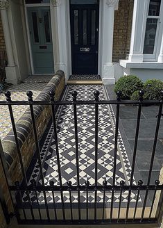 a black and white checkered tile floor in front of a house with iron railings