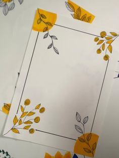 some yellow flowers and leaves are cut out on white paper to make an artistic border