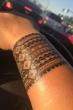 a person's arm with a tattoo on it in front of some parked cars