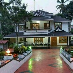 a large white house sitting on top of a lush green field next to tall trees