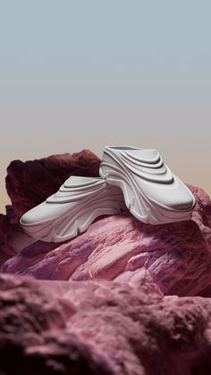 a pair of white shoes sitting on top of a rocky mountain covered in pink rocks