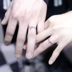 two people holding hands with tattoos on their fingers