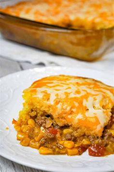 a white plate topped with a piece of casserole covered in cheese and vegetables